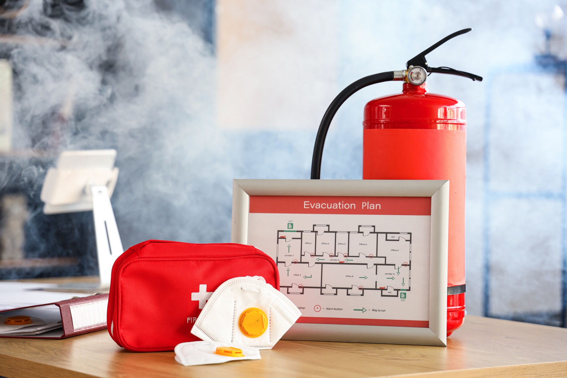 Essential emergency preparedness and safety equipment arranged on a desk with smoke.